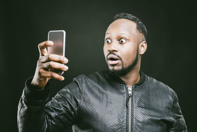 Close-up of man using mobile phone against black background