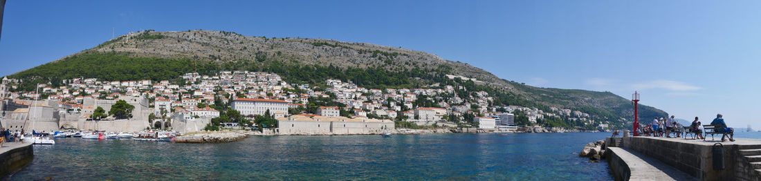 Panoramic view of sea and buildings against blue sky