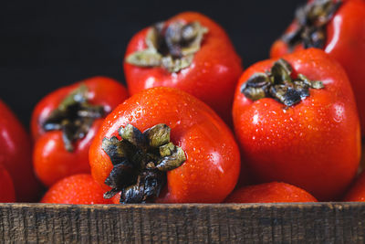 Close-up of wet persimmons in wooden container