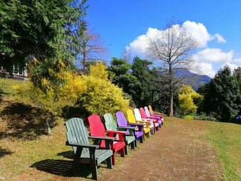 Empty chairs and tables in park against sky