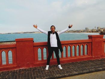 Full length portrait of smiling man standing against sky