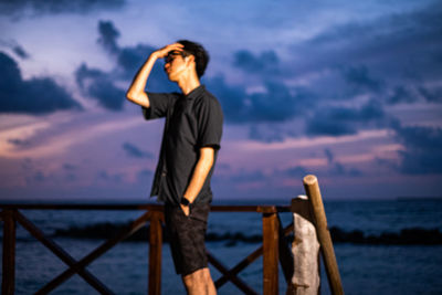 Full length of man photographing sea against sky during sunset