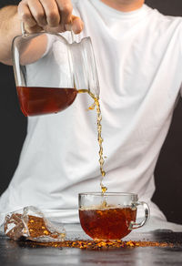 Midsection of man pouring tea in cup