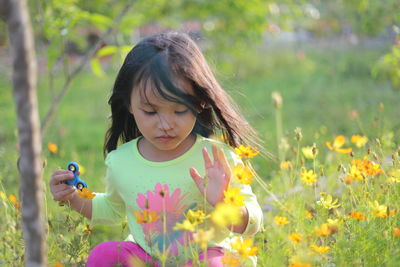 Close-up of girl holding flower in field