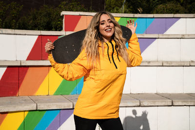 Portrait of a cheerful woman with a skateboard on colorful stairs