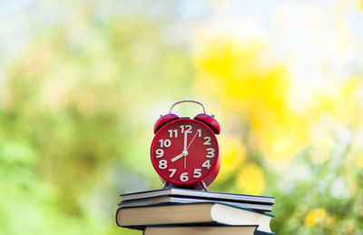 Close-up of stacked books and alarm clock at home