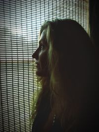 Thoughtful mature woman looking through window at home