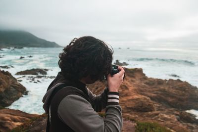 Man photographing sea against sky