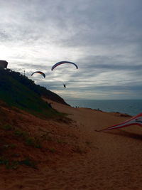 Woman flying over beach against sky