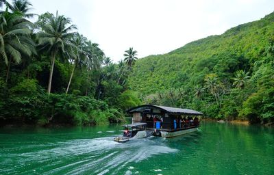 Boat in river by trees against sky