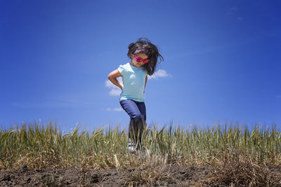 Young woman on field against clear blue sky