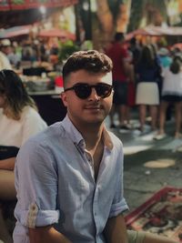 Portrait of young man wearing sunglasses sitting outdoors