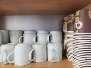 Close-up of mugs and disposable cups in shelf