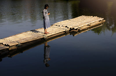 High angle view of woman standing on wooden raft in lake