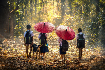 Rear view of children walking in forest