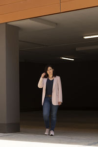 Portrait of young woman standing against wall