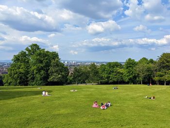 People in queen's park against cloudy sky