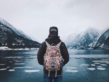 Rear view of woman standing on snowcapped mountain against sky