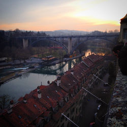 Aerial view of river amidst city against sky during sunset