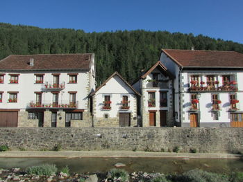 Houses by trees and buildings against sky
