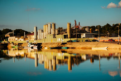 Reflection of buildings in lake against blue sky