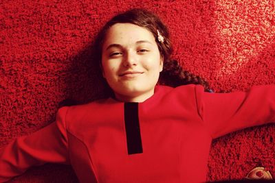 Portrait of smiling young woman lying on red rug