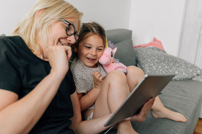 Grandmother using digital tablet with granddaughter at home