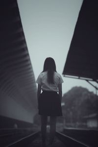 Rear view of woman standing on railroad track