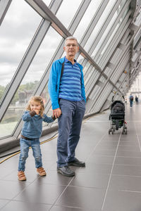 Grandfather and granddaughter standing on footbridge