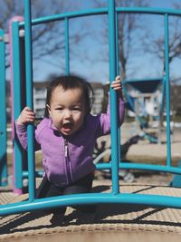 Portrait of baby girl standing on jungle gym at playground