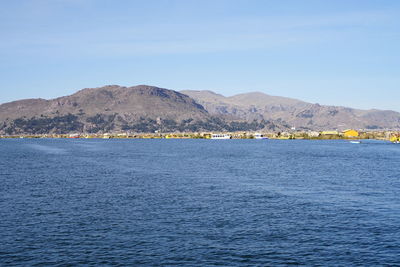 Scenic view of sea and mountains against blue sky