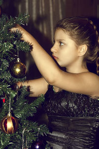 Portrait of young woman with christmas tree at home