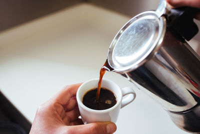 Cropped hand of of person pouring coffee in cup