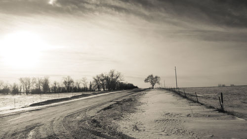 Tire tracks on snow field against sky