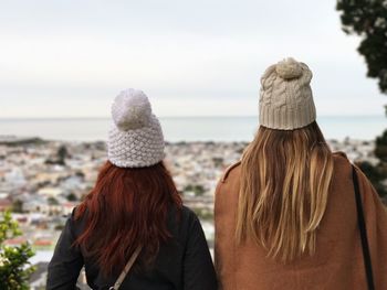 Rear view of female friends standing at beach