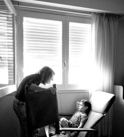 Woman sitting by window at home