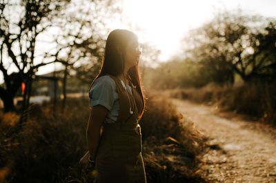 Woman standing on field against trees