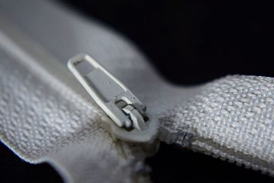 Close-up of white zip over black background