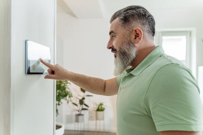 Mature man using tablet pc mounted on wall at home