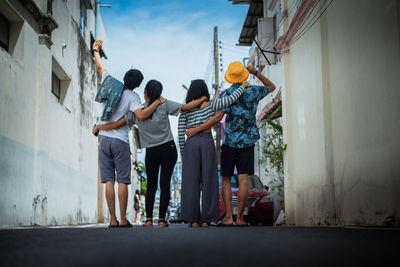 Rear view of woman standing on footpath amidst buildings