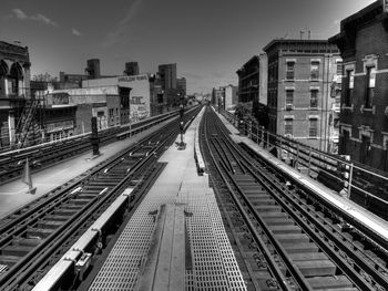 Railroad tracks in city against sky