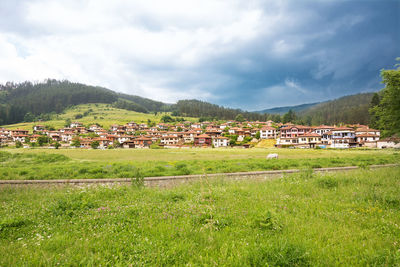 Houses and trees on field against sky