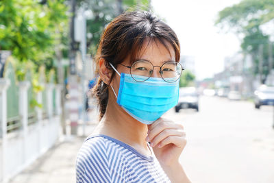 Portrait of young woman holding eyeglasses on street