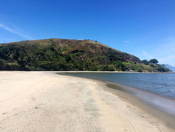 Scenic view of beach against blue sky