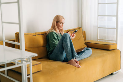 Young woman sitting on sofa at home