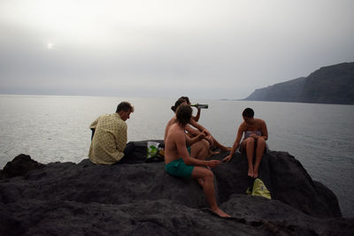 People sitting on beach looking at sea