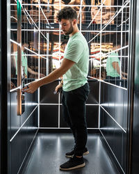 Side view of young man standing against railing