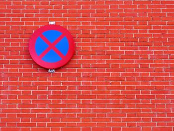 Low angle view of no parking sign on brick wall