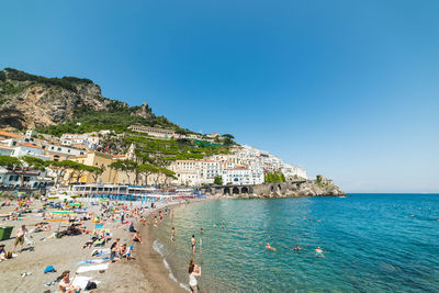 People on beach against clear blue sky