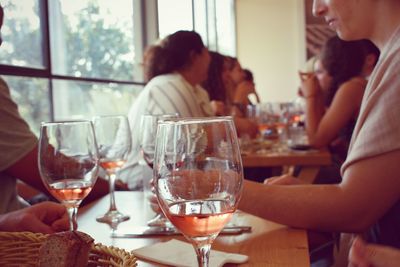 Midsection of man drinking glass on table at restaurant